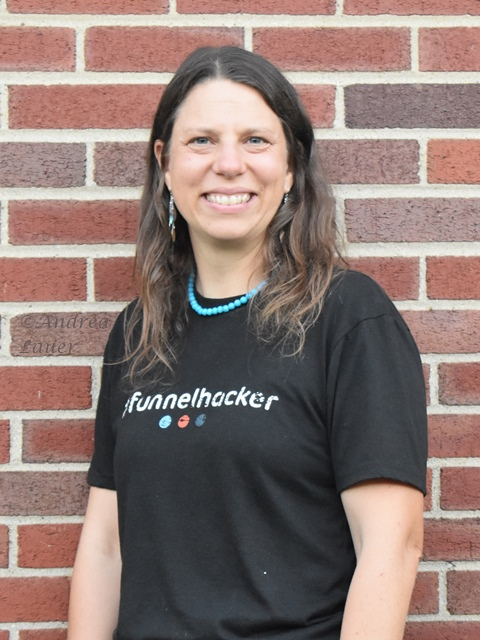 Kristen Lauer wearing her #Funnelhacker shirt, smiling in front of a red brick wall
